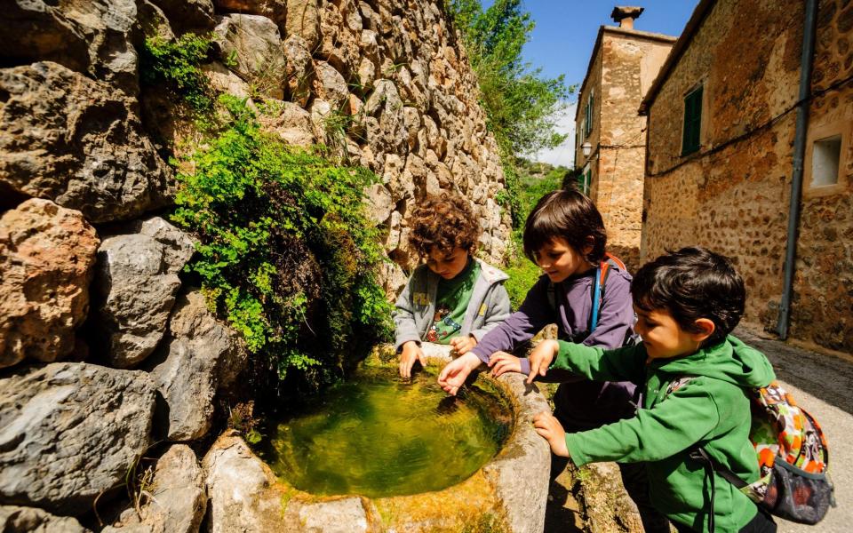children in a water fountain, Deia, Balearic Islands - Alamy