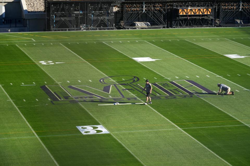 Workers paint the Super Bowl LVIII logo on the field at Allegiant Stadium. The Super Bowl will be played on natural grass.