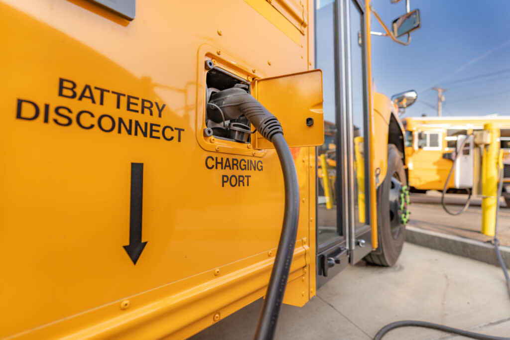 Electric school bus plugged in at a charging station.