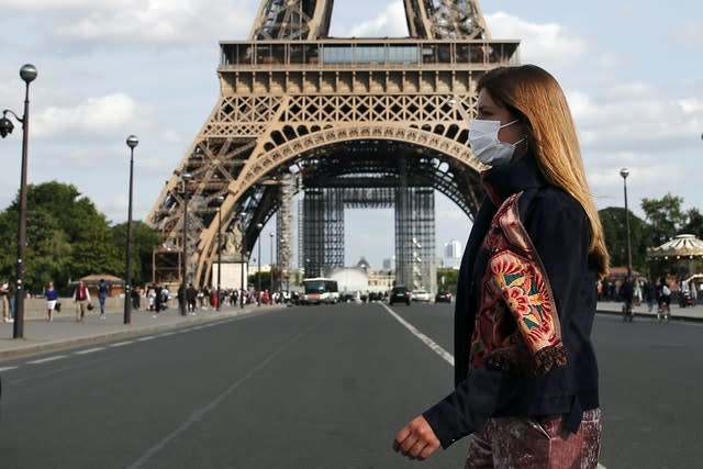 A woman wearing a protective face mask walks next to the Eiffel Tower in Paris (Francois Mori/AP)