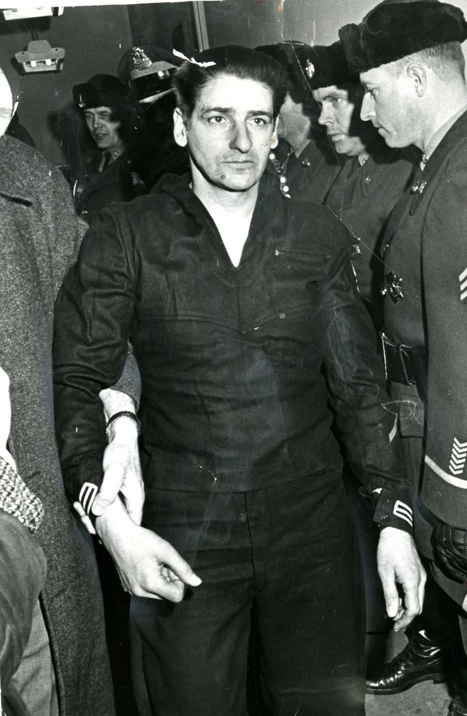 albert desalvo being held at the wrist by another person as he walks forward