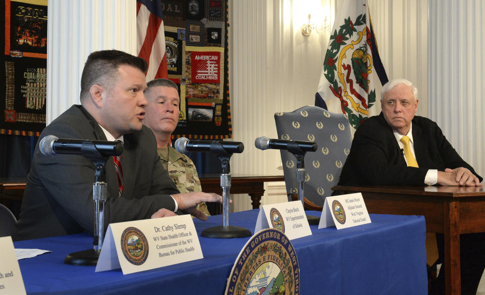West Virginia State Superintendent of Schools Clayton Burch, left, answers questions about the closing of all schools in the state as WV National Guard Maj. Gen. James Hoyer and with Gov. Jim Justice, right, looks on, during a press conference at the state Capitol in Charleston, W.Va., Friday, March 13, 2020. (Chris Dorst/Charleston Gazette-Mail via AP)