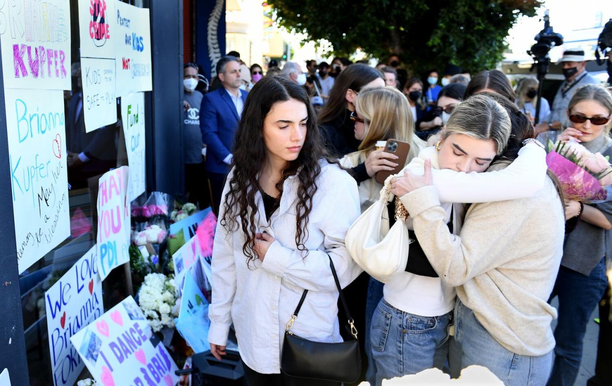 People console one another at vigil.