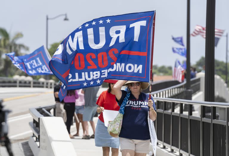 Partidarios de Donald Trump blanden banderas con su nombre cerca de la mansión Mar-a-Lago, en Palm Beach