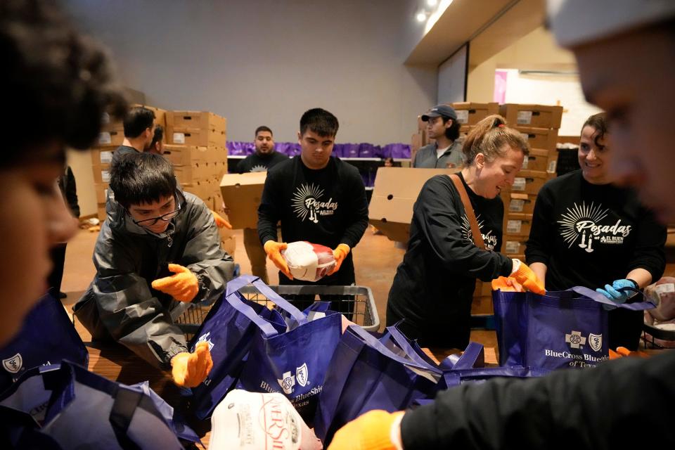 From left, volunteers Miguel Pompa, 14, Nolan Clay, 18, Aimee Zivin and Karen Green prepare meal kits at El Buen Samaritano. The meal kits contained a frozen turkey and all the side dishes to prepare a holiday dinner at home.