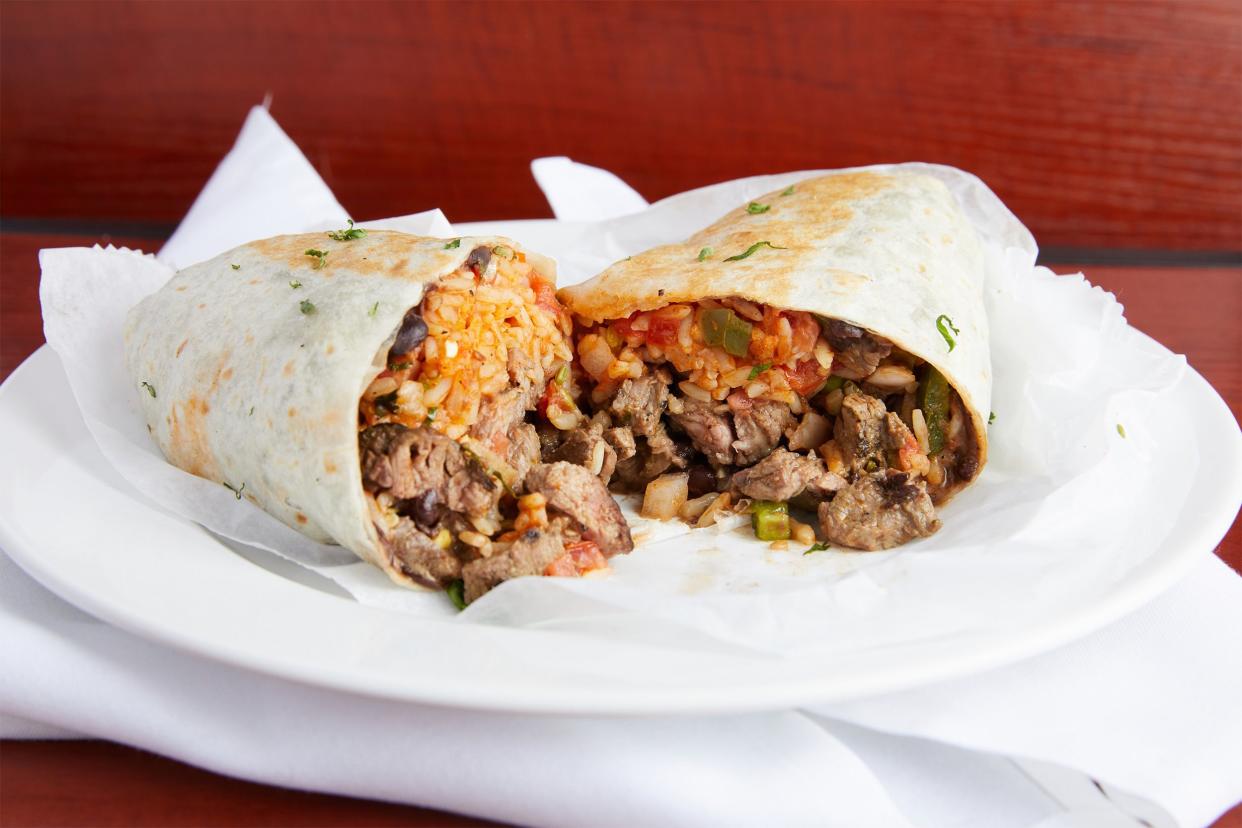 steak burrito cut in half on a white plate