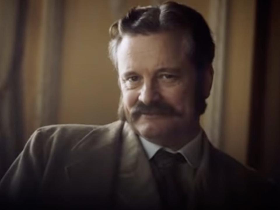Colin Firth with curled hair and a mustache in "The Happy Prince."