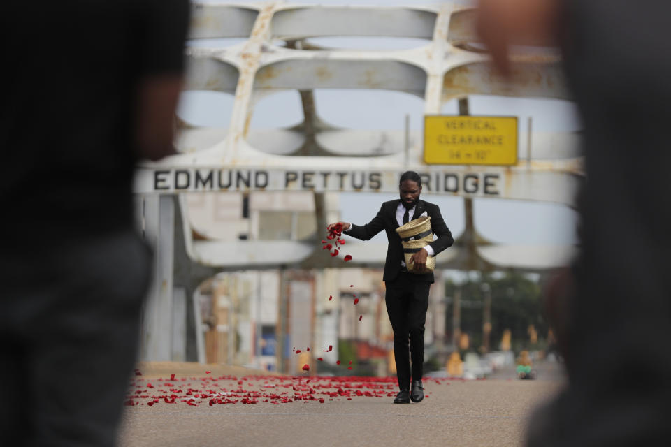 A man places flower petals on the Edmund Pettus Bridge ahead of Rep. John Lewis' casket crossing during a memorial service for Lewis, Sunday, July 26, 2020, in Selma, Ala. Lewis, who carried the struggle against racial discrimination from Southern battlegrounds of the 1960s to the halls of Congress, died Friday, July 17, 2020. (AP Photo/Brynn Anderson)
