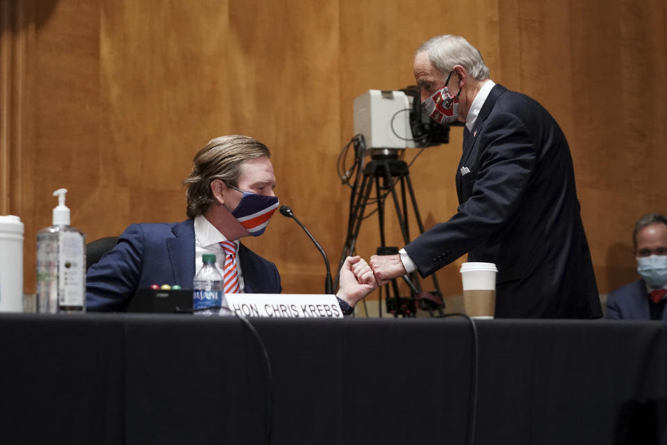 Sen. Tom Carper, D-Del., fist bumps Christopher Krebs, former director of the Cybersecurity and Infrastructure Security Agency, during a Senate Homeland Security & Governmental Affairs Committee hearing to discuss election security and the 2020 election process on Wednesday, Dec. 16, 2020, on Capitol Hill in Washington. (Greg Nash/Pool via AP)