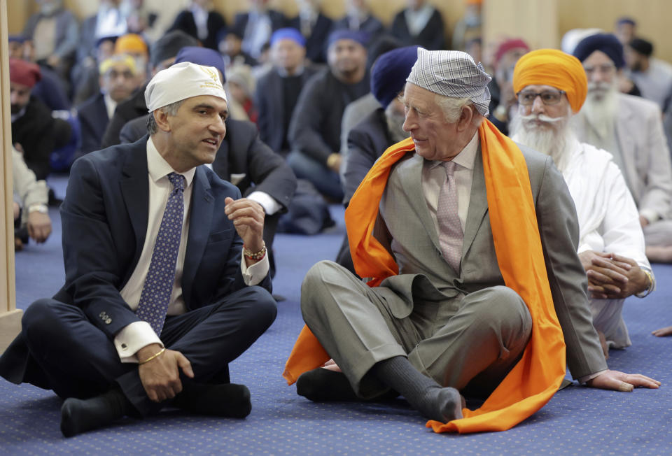 FILE - Britain's King Charles III, right, speaks with Professor Gurch Randhawa, a member of the Sikh Congregation, as they sit on the floor in the Prayer Hall during the king's visit to the newly built Guru Nanak Gurdwara, in Luton, England, Tuesday, Dec. 6, 2022. King Charles III's commitment to diversity will be on display at his coronation, when religious leaders representing the Buddhist, Hindu, Jewish, Muslim and Sikh traditions will for the first time play an active role in the ceremonies. (Chris Jackson/Pool Photo via AP, File)