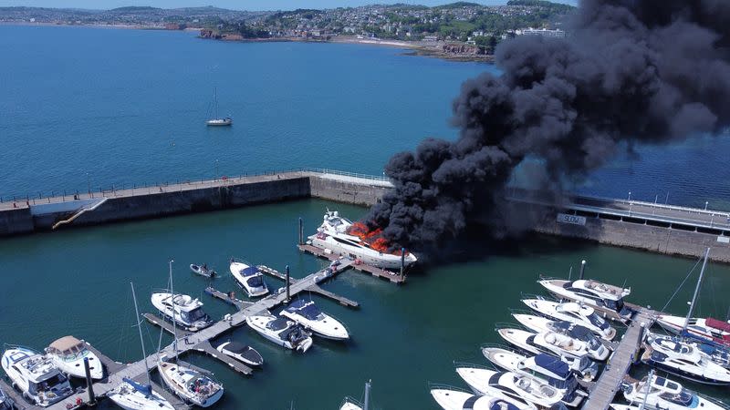 Thick black smoke rises from a fire on a yacht, at Torquay harbour