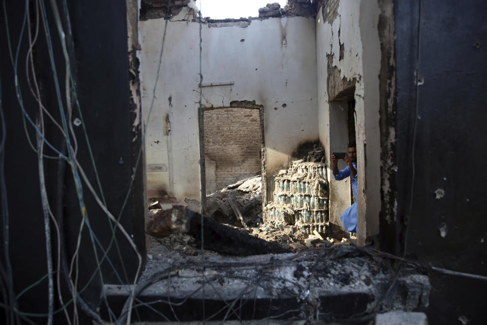 An Afghan journalist takes a photo by his mobile phone of a damaged part of the prison after an attack in the city of Jalalabad, east of Kabul, Afghanistan, Monday, Aug. 3, 2020. An Islamic State group attack on the prison in eastern Afghanistan holding hundreds of its members raged on Monday after killing people in fighting overnight, a local official said. (AP Photo/Rahmat Gul)