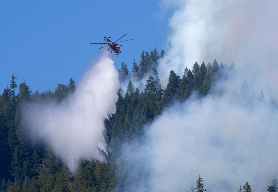A helicopter drops water on the western flank of the Lookout Fire near Rainbow Friday.
