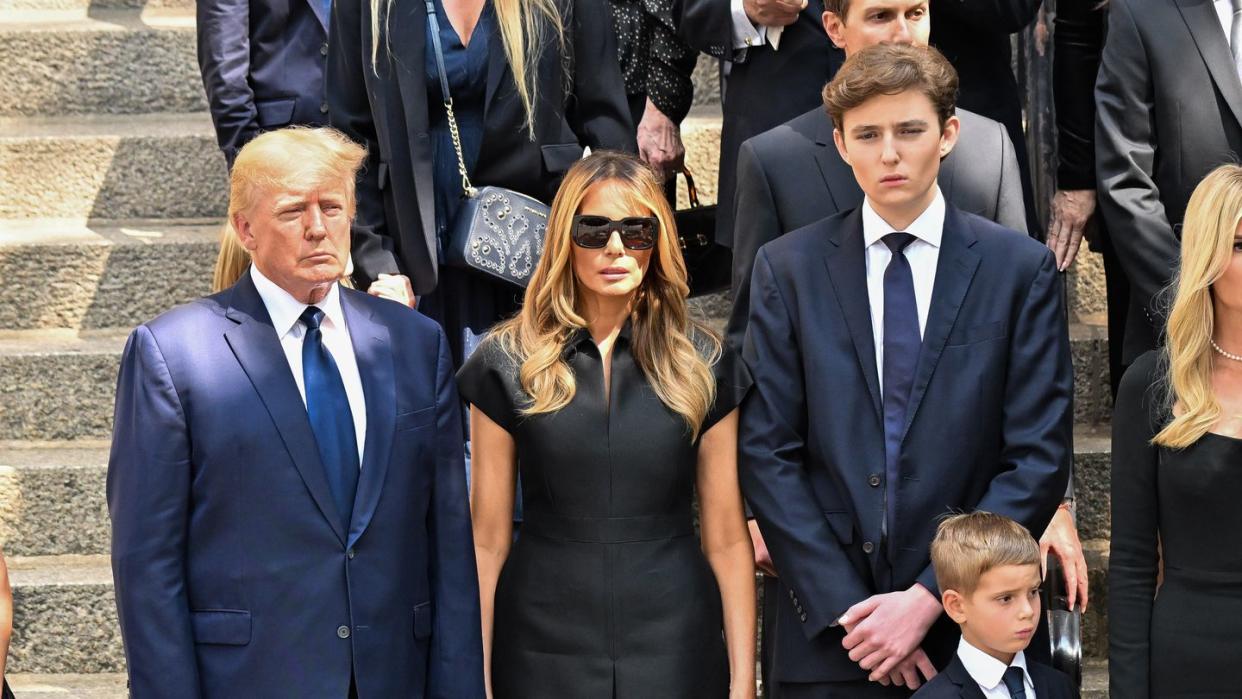 barron trump walking down a set of church stairs alongside his parents