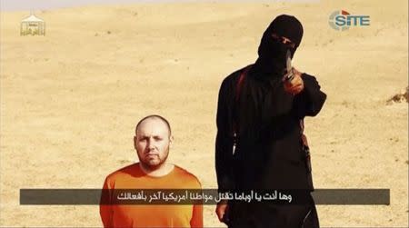 A masked, black-clad militant, who has been identified by the Washington Post newspaper as a Briton named Mohammed Emwazi, stands next to a man purported to be Steven Sotloff in this still image from a video obtained from SITE Intel Group website February 26, 2015. REUTERS/SITE Intel Group via Reuters TV