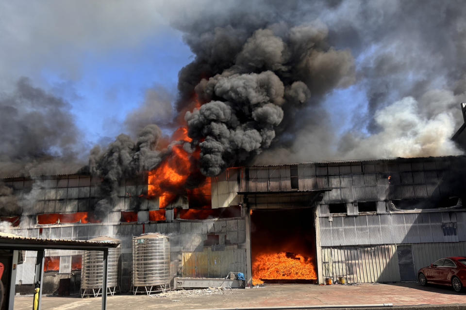 台南市新營區一家資源再生公司廠房21日中午發生火警，鐵皮建物工廠全面燃燒，冒出大量濃煙。（中央社／讀者提供）