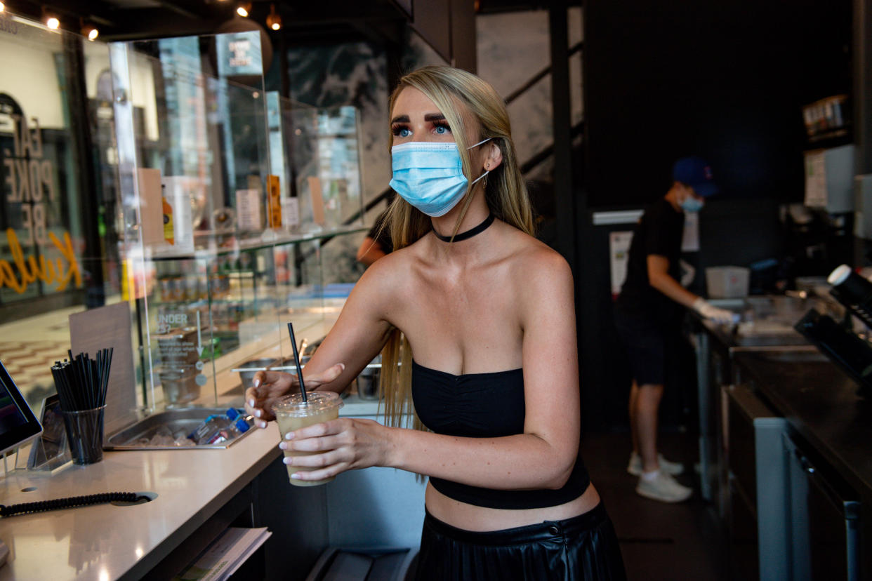 Felicity Whiston, wearing a face mask whilst serving drinks at take away restaurant Kuula Poke in Birmingham, as non-essential shops in England open their doors to customers for the first time since coronavirus lockdown restrictions were imposed in March. (Photo by Jacob King/PA Images via Getty Images)