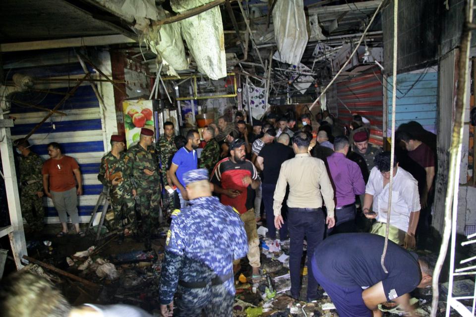 People and security forces gather at the site of a bombing in Wahailat market in Sadr City, Iraq, Monday, July. 19, 2021. A roadside bomb attack targeted a Baghdad suburb Monday, killing several and wounding dozens of others at a crowded market, Iraqi security officials said. (AP Photo/Khalid Mohammed)