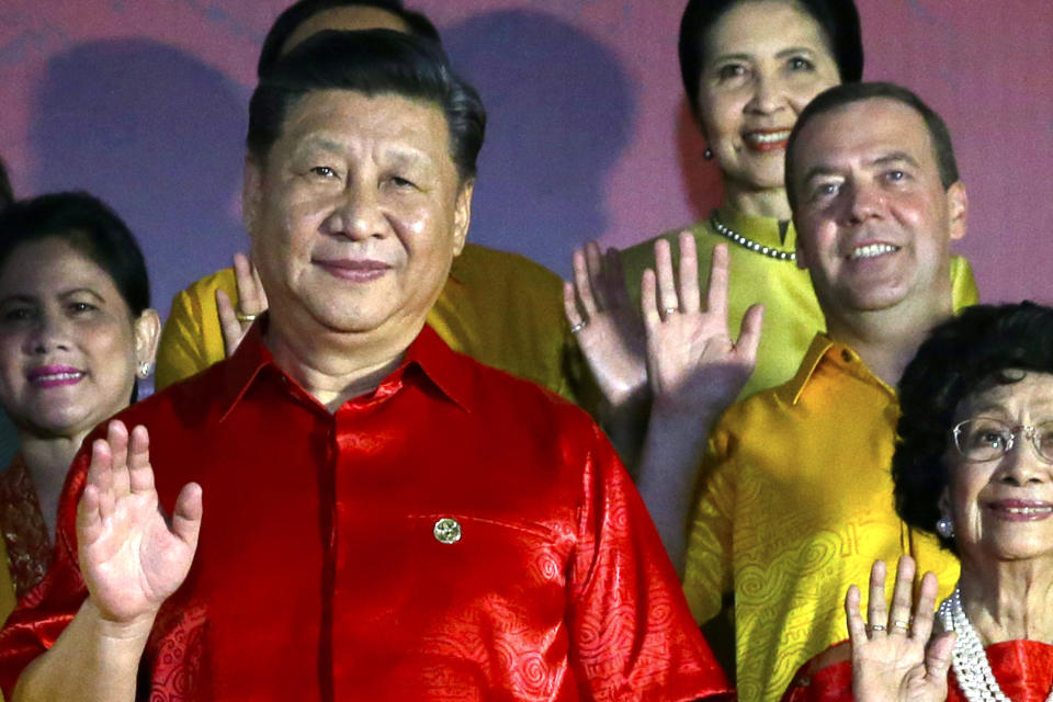 Chinese President Xi Jinping, left, and Russian Prime Minister Dmitry Medvedev wave as they pose for a family photo with leaders and their spouses during the APEC Economic Leaders Meeting summit in Port Moresby, Papua New Guinea, Saturday, Nov. 17, 2018. (AP Photo/Mark Schiefelbein)