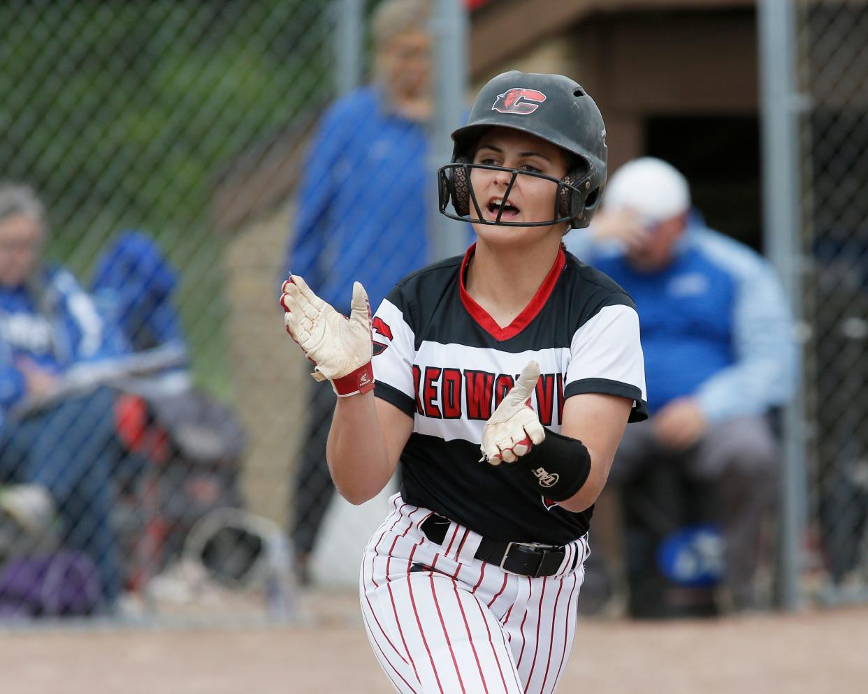 Clinton's Raven Aldridge claps her hands toward the Redwolves dugout as she heads to first base after drawing a walk in Monday's doubleheader against Dundee.