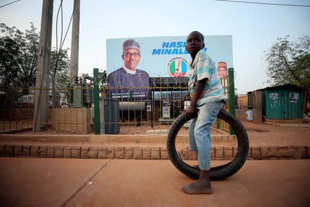 A boy sits on a tyre in front of a billboard on the eve of Nigeria's 2019 presidential election in Daura, Katsina State, Nigeria February 22, 2019.REUTERS/Afolabi Sotunde