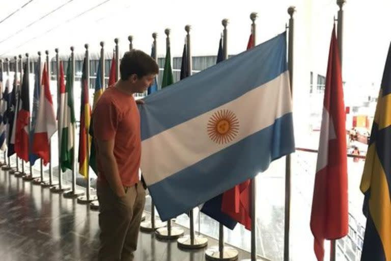 El tucumano en la Biblioteca Nacional de Qatar junto a una bandera argentina