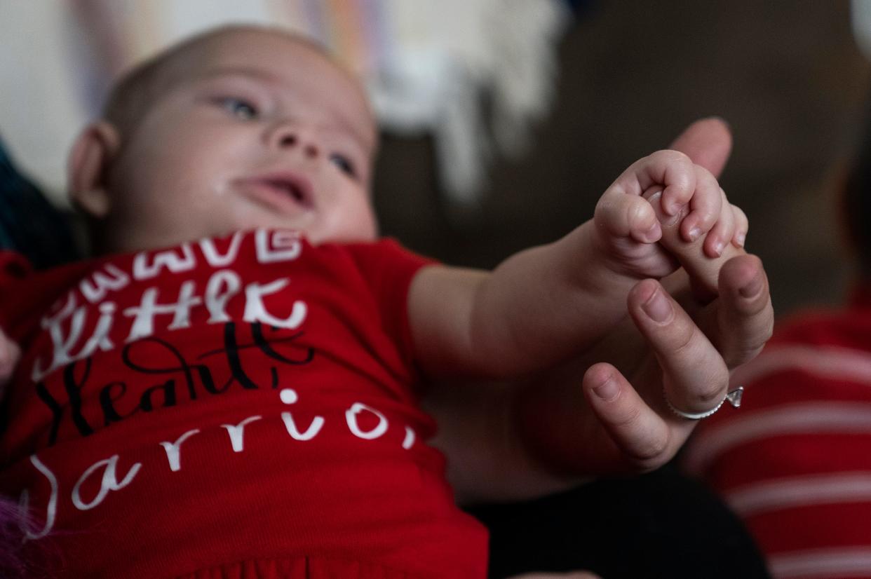 Emily Crawford holds her 4-month-old baby Sage Crawford's hand in their home. Emily has had to navigate finding a new health plan while caring for Sage through multiple heart surgeries. The Medicaid that previously covered Sage through Anthem does not cover treatment at Nationwide Children's Hospital.