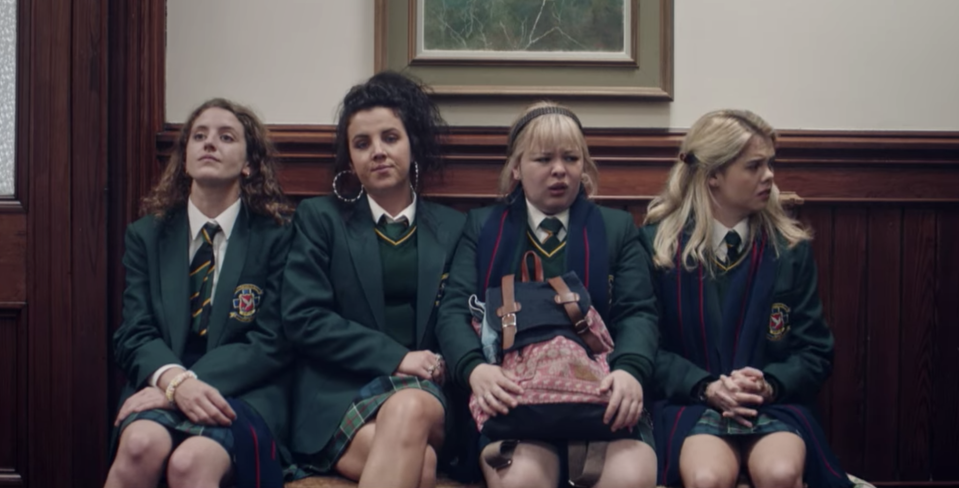 four teens sitting on a bench at school