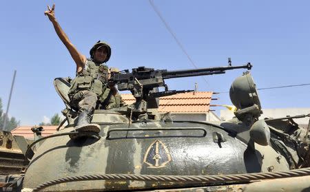 A Lebanese army soldier flashes a victory sign while riding on a tank as they advance towards the Sunni Muslim border town of Arsal, in eastern Bekaa Valley as part of reinforcements August 6, 2014. REUTERS/Hassan Abdallah