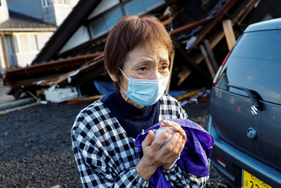 日本石川縣輪島，1名災民從鄰居手中接獲食物。路透社
