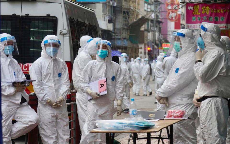 Government investigators wearing protective suits gather in the Yau Ma Tei area in Hong Kong - AP Photo/Vincent Yu