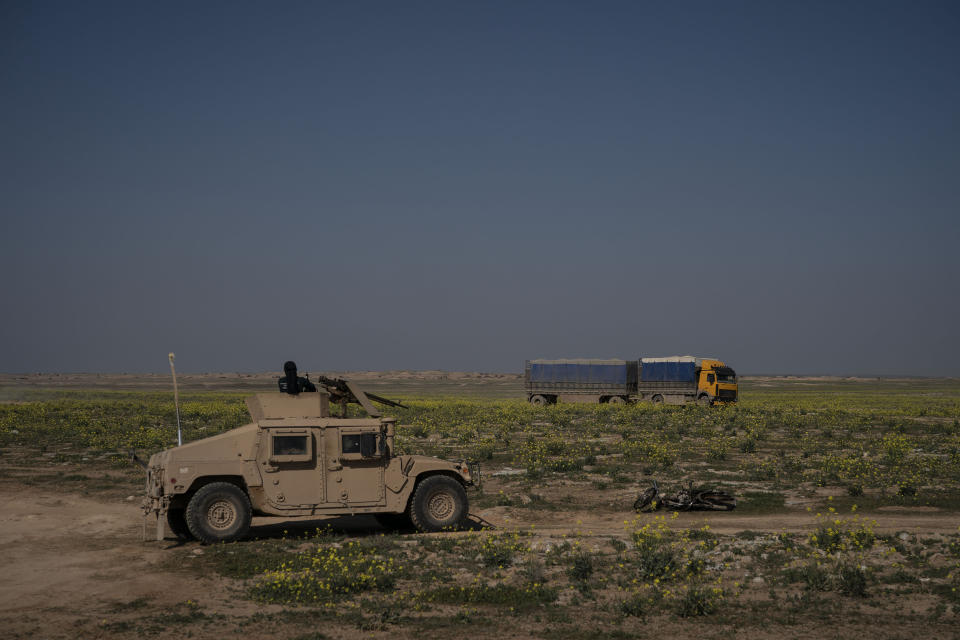 A U.S.-backed Syrian Democratic Forces (SDF) Humvee stands by as a truck that is part of a convoy evacuating hundreds out of the last territory held by Islamic State militants, passes in Baghouz, eastern Syria, Wednesday, Feb. 20, 2019. The evacuation signals the end of a week long standoff and opens the way to U.S.-backed Syrian Democratic Forces (SDF) recapture the territory. (AP Photo/Felipe Dana)