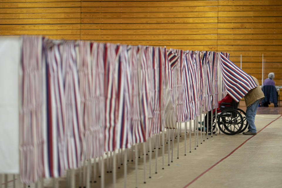 Unos votantes salen de una casilla durante las primarias presidenciales de Nueva Hampshire, en un centro de votación en Derry, Nueva Hampshire, el martes 23 de enero de 2024. (AP Foto/David Goldman)