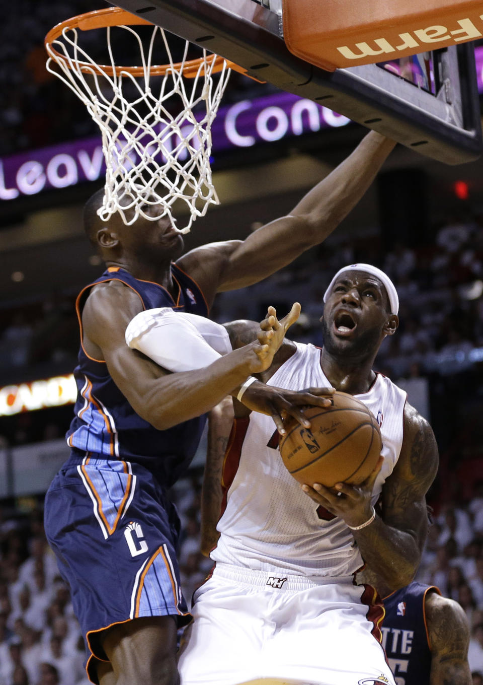 Miami Heat's LeBron James, right, is fouled by Charlotte Bobcats' Bismack Biyombo, left, during the first half in Game 1 of an opening-round NBA basketball playoff series, Sunday, April 20, 2014, in Miami. (AP Photo/Lynne Sladky)