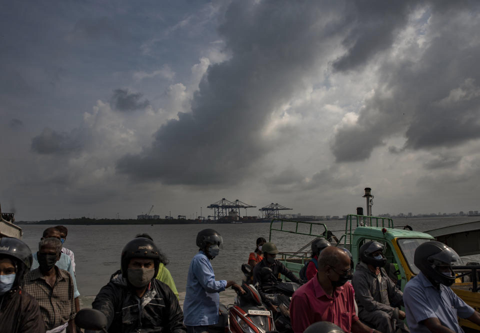 Rain clouds fill the sky as people travel in a ferry in Kochi, Kerala state, India, Monday, Oct.18, 2021. (AP Photo/R S Iyer)