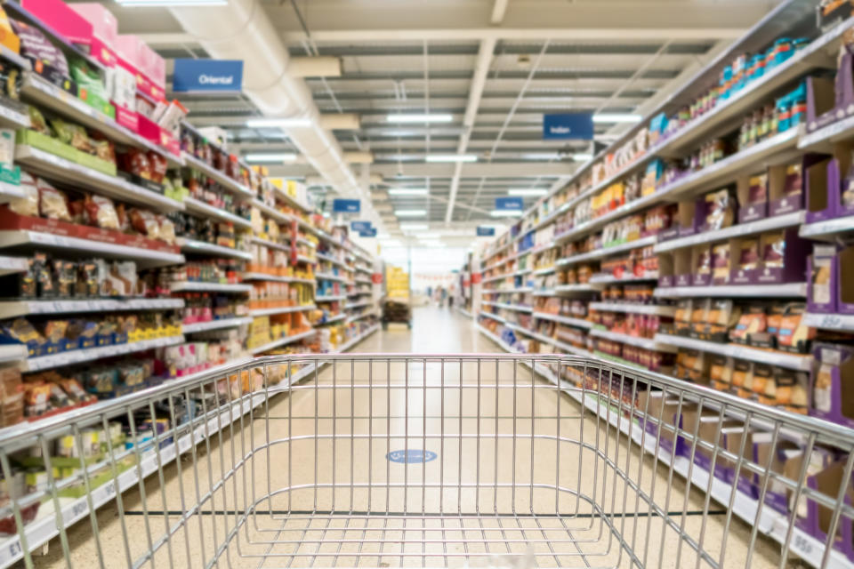 Supermarket aisle and empty trolley from point of view angle.