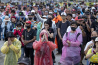 Pro-democracy protesters raise a three-fingers, symbol of resistance salute as others observe Buddhist religious rituals during a rally at Sanam Luang in Bangkok, Thailand, Sunday, Sept. 20, 2020. Thousands of demonstrators who occupied a historic field in Thailand's capital overnight continued with their rally on Sunday to support the demands of a student-led protest movement for new elections and reform of the monarchy. (AP Photo/Gemunu Amarasinghe)