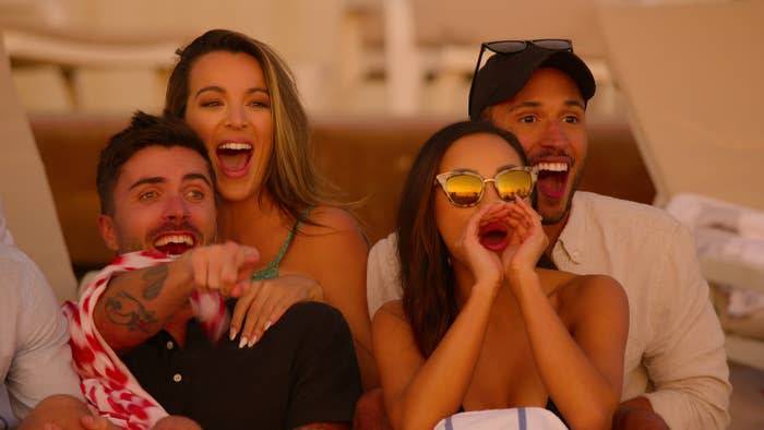 Tyler, Alex, Lauren and Sean smile and yell while seated on a beach