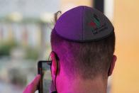 A man wearing a kippah bearing the tourist logo of the United Arab Emirates takes a picture on his mobile phone at the Israeli pavilion at Expo 2020 in Dubai, United Arab Emirates, Thursday, Oct. 7, 2021. Israel ceremonially opened its gleaming pavilion at the world's fair in Dubai on Thursday, over a year after normalizing ties with the United Arab Emirates and amid a pandemic that has disrupted much of the tourist and cultural exchanges promised by the U.S.-brokered accords. (AP Photo/Jon Gambrell)