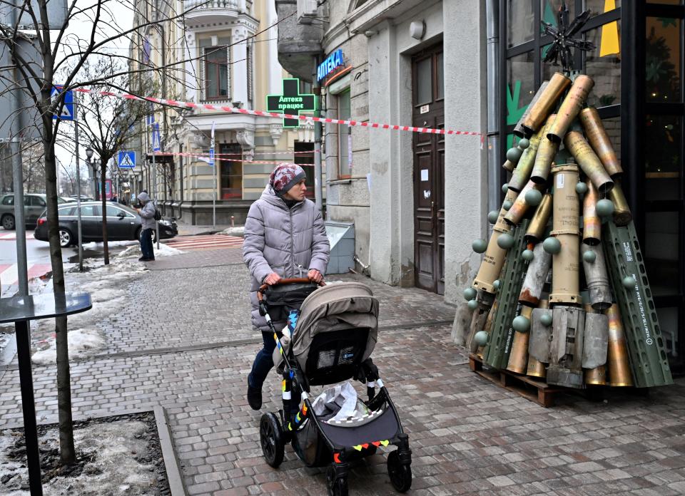 A woman pushes a pram as she walks past a symbolic Christmas tree made from spent shells casing in Kyiv (AFP via Getty Images)
