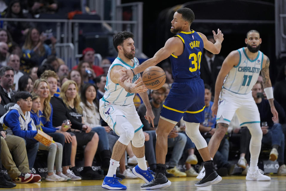 Charlotte Hornets guard Vasilije Micic, left, passes the ball while defended by Golden State Warriors guard Stephen Curry (30) during the first half of an NBA basketball game Friday, Feb. 23, 2024, in San Francisco. (AP Photo/Godofredo A. Vásquez)