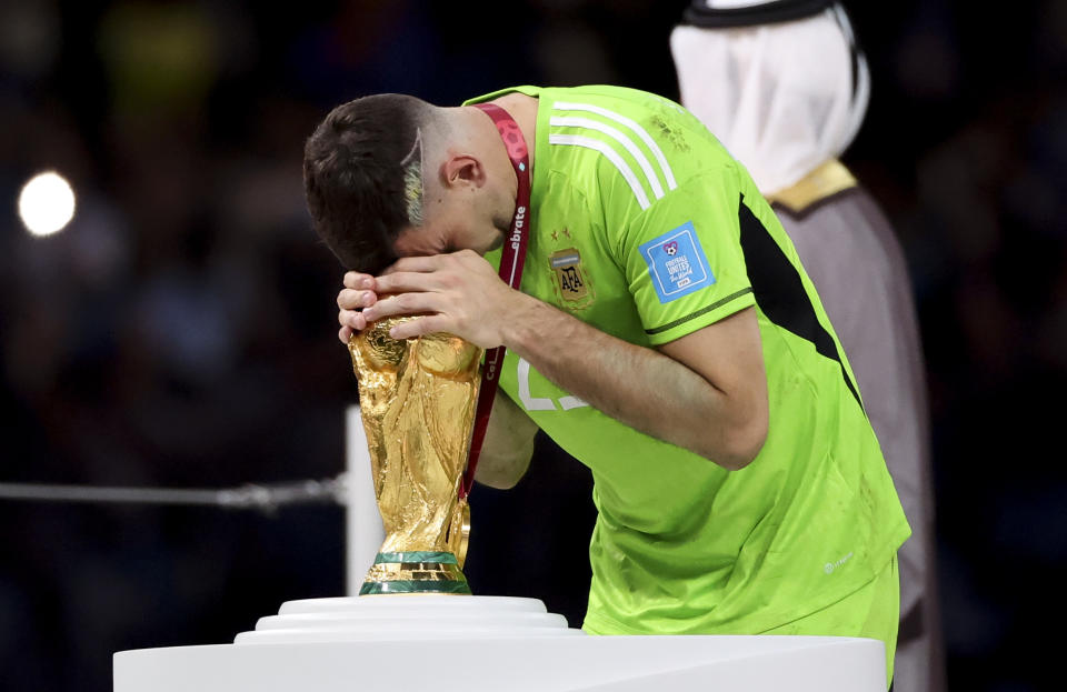 LUSAIL CITY, QATAR - DECEMBER 18: Argentina goalkeeper Emiliano Martinez aka Damian Martinez kissing the World Cup during the trophy ceremony following the FIFA World Cup Qatar 2022 Final match between Argentina and France at Lusail Stadium on December 18, 2022 in Lusail City, Qatar. (Photo by Jean Catuffe/Getty Images)