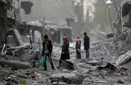 People walk through debris in the center of Afrin, Syria March 24, 2018. REUTERS/Khalil Ashawi