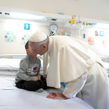 Pope Francis receives a kiss from a child at the Casa Sollievo della Sofferenza hospital in San Giovanni Rotondo, Italy March 17, 2018. Osservatore Romano/Handout via REUTERS