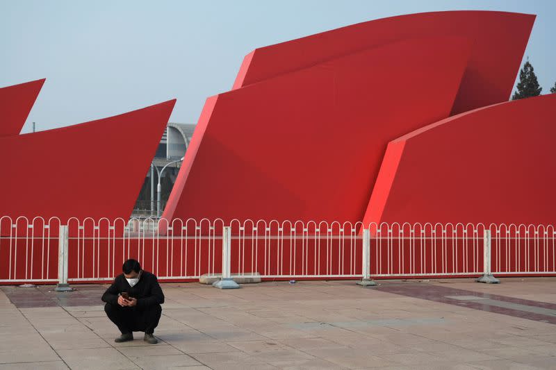 Man wearing a mask uses his phone in front of the Beijing Exhibition Center, following the coronavirus outbreak, in Beijing