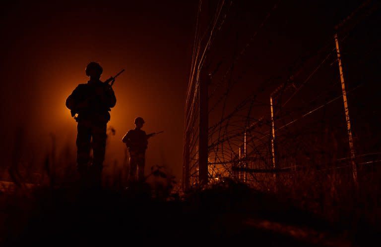 Indian soldiers patrol the border fence at an outpost along the India-Pakistan border in Suchit-Garh, on January 11, 2013. Police in Indian Kashmir have warned residents to build underground bunkers to prepare for a possible nuclear war in the disputed region, which is on edge after a string of deadly border clashes