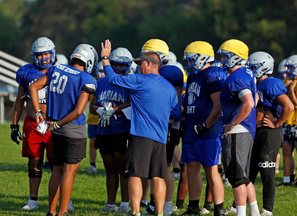 Mishawaka Marian football head coach Mike Davidson, center, gives instructions to his players on offense during practice Wednesday, June 3, 2023 at Marian High School in Mishawaka.