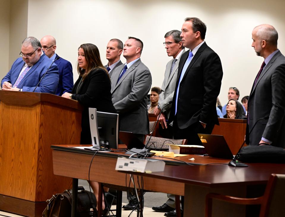 Paramedics Peter Cichuniec, fourth from left, and Jeremy Cooper, fifth from left, flanked by their attorneys, left, and prosecutors, right, attend an arraignment at the Adams County Justice Center in Brighton, Colo., on Friday, Jan. 20, 2023. Aurora Police officers Nathan Woodyard, Randy Roedema and former officer Jason Rosenblatt along with paramedics Jeremy Cooper and Peter Cichuniec were indicted by a Colorado state grand jury in 2021 on 32 combined accounts related to Elijah McClain's arrest and death in August 2019. (Andy Cross/The Denver Post via AP)