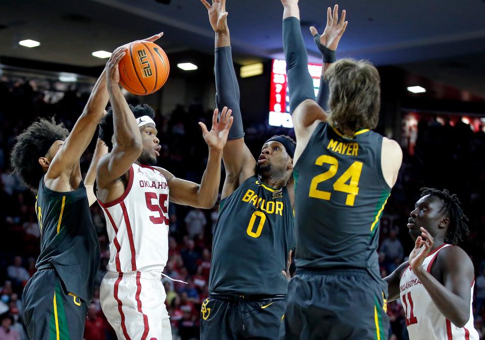 Oklahoma's Elijah Harkless (55) passes the ball as Baylor's Kendall Brown (2), Flo Thamba (0) and Matthew Mayer (24) defedn in the second half during the men's college game between the Oklahoma Sooners and the Baylor Bears at the Lloyd Noble Center in Norman, Okla., Saturday, Jan. 22, 2022. 