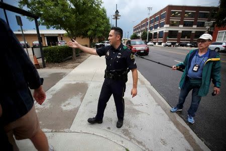 A Dallas police officer moves media away from in front of the Dallas Police Department headquarters which was locked down after an anonymous threat was reported in Dallas, Texas, U.S. July 9, 2016. REUTERS/Carlo Allegri